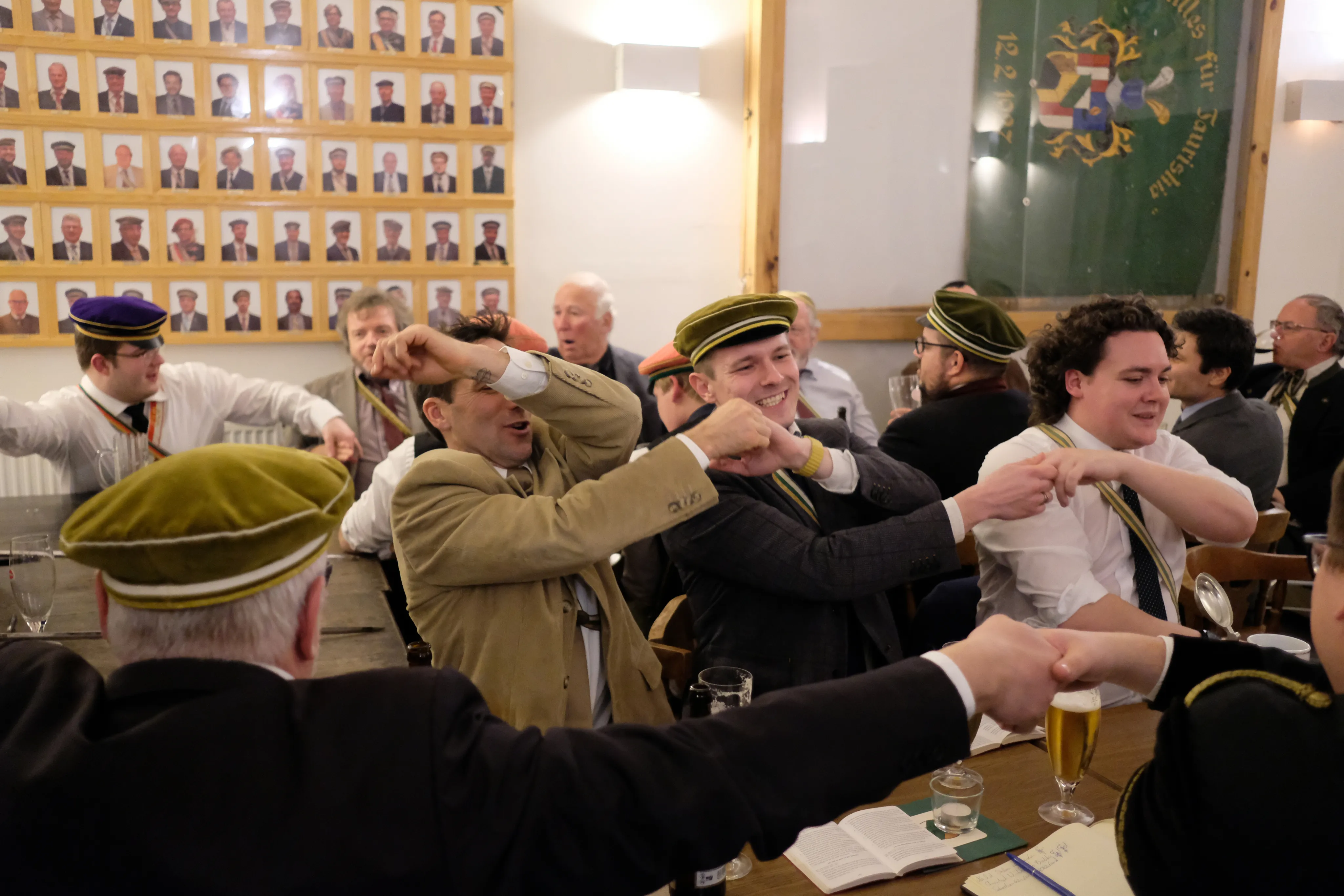 Studierende lachen gemeinsam in einem warm beleuchteten, holzvertäfelten Raum.